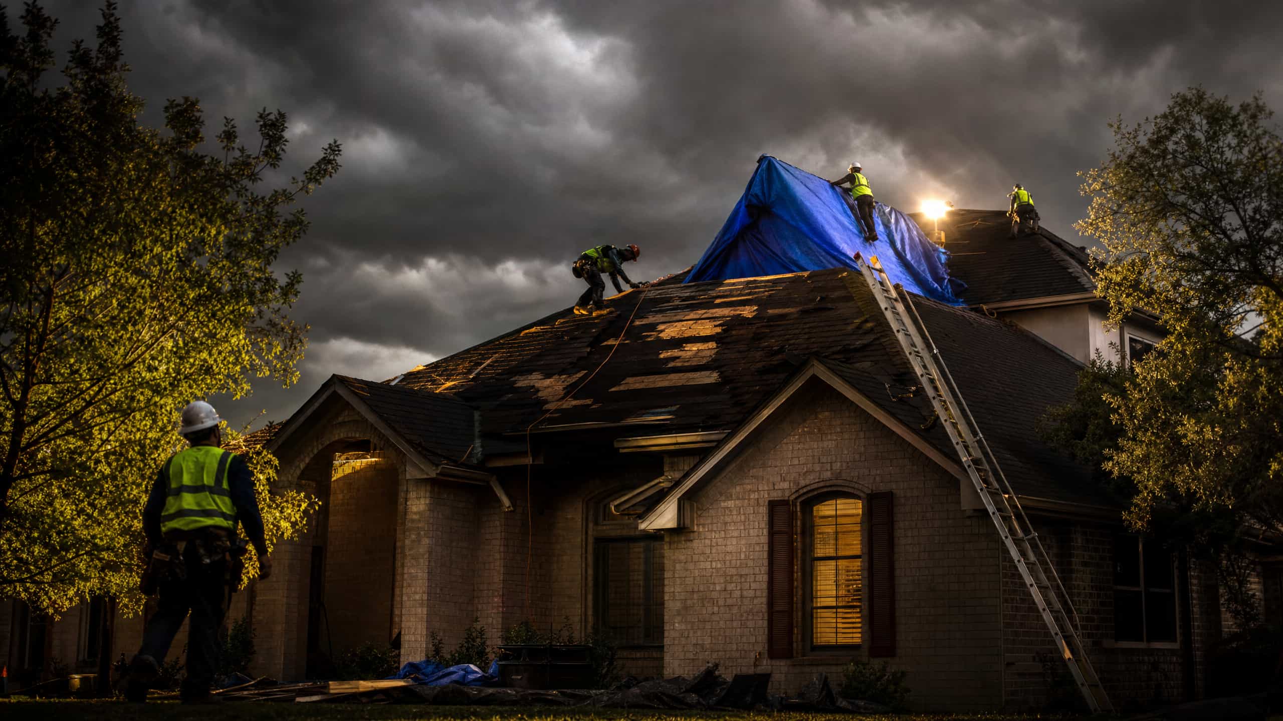Emergency roofing crew securing a storm-damaged home at night in Austin TX